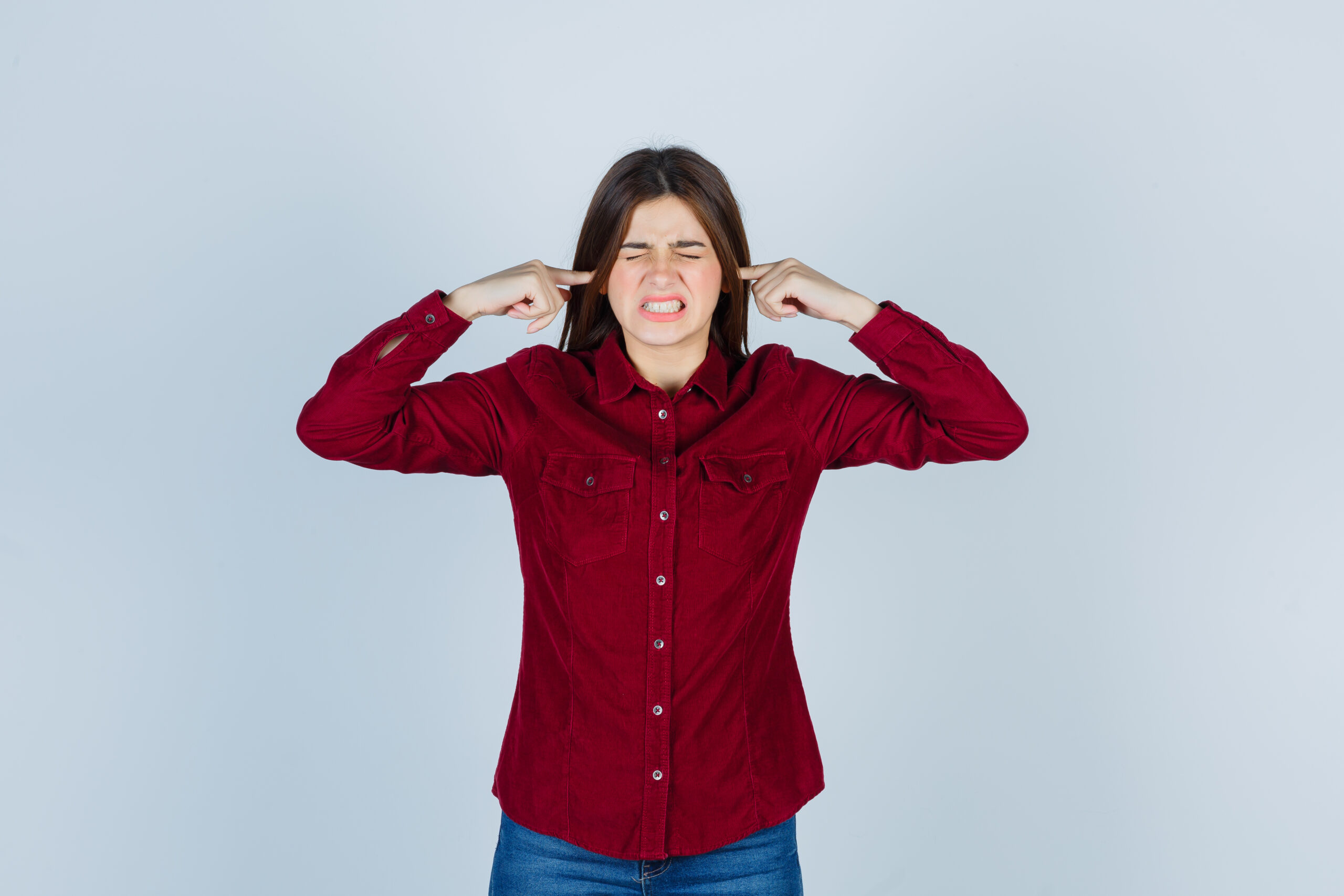 woman in red shirt covering ears to block noise
