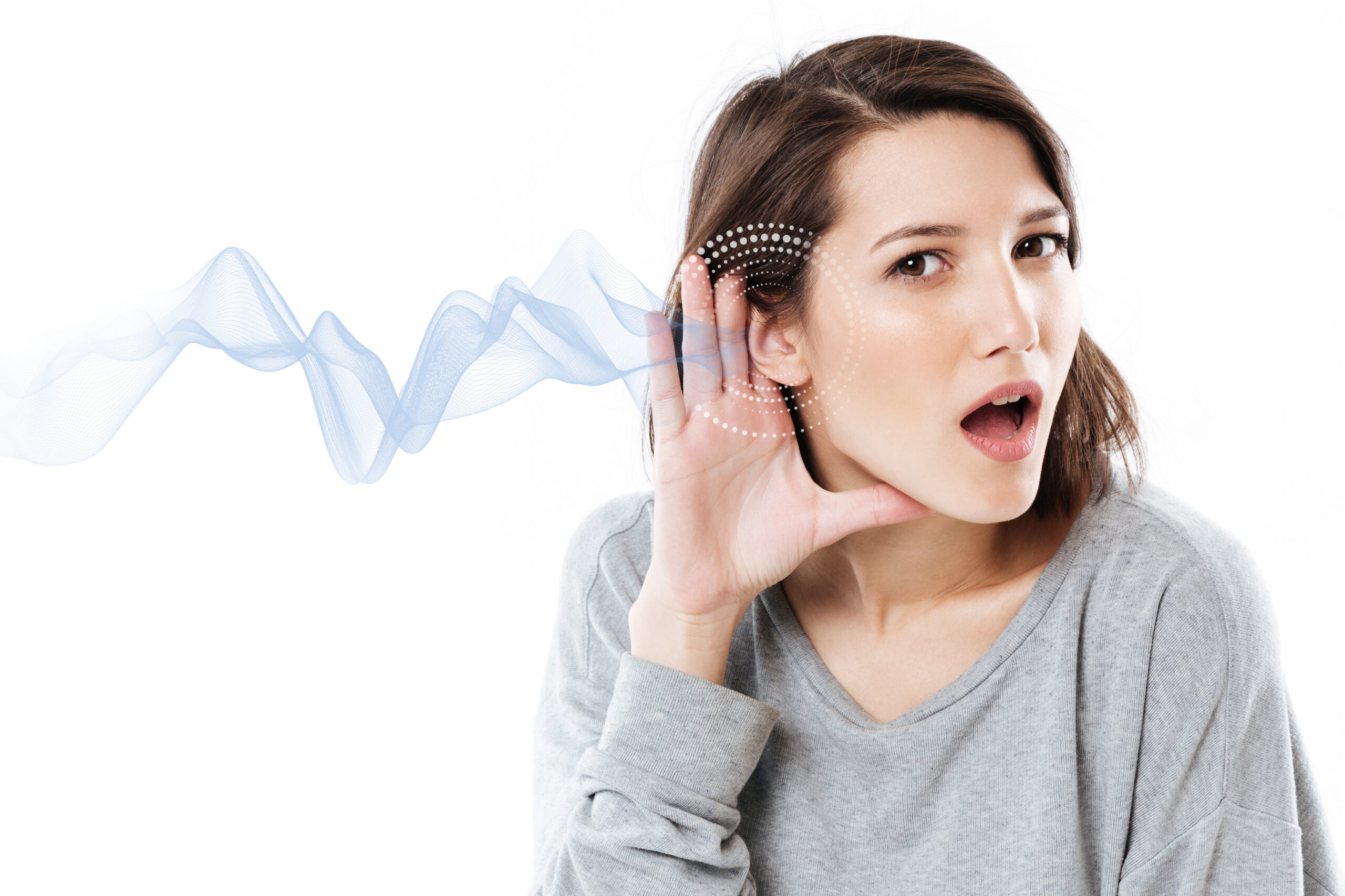Young woman cupping ear to listen to sound wave.